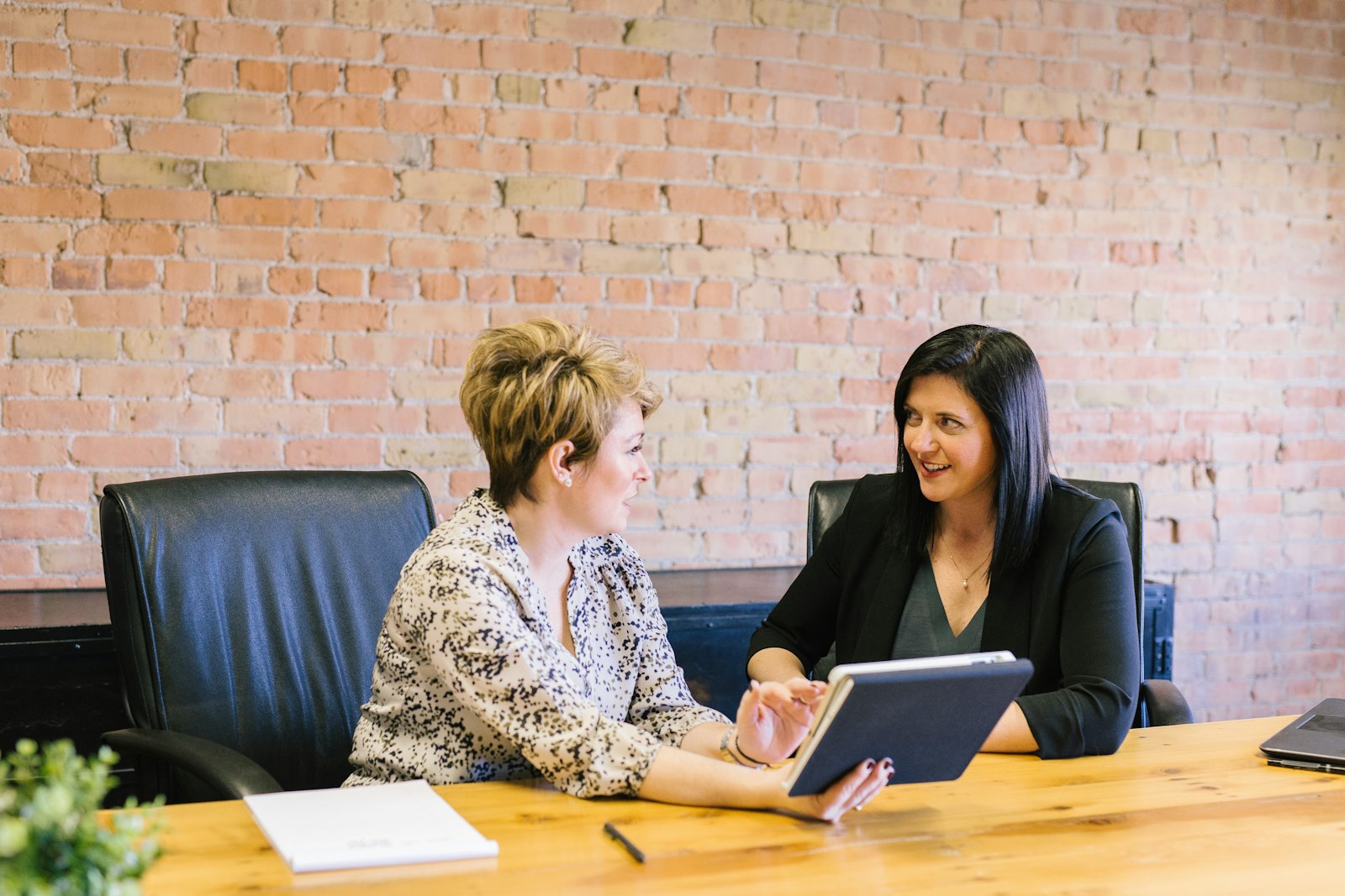 Two professionals in conversation across a table during a meeting
